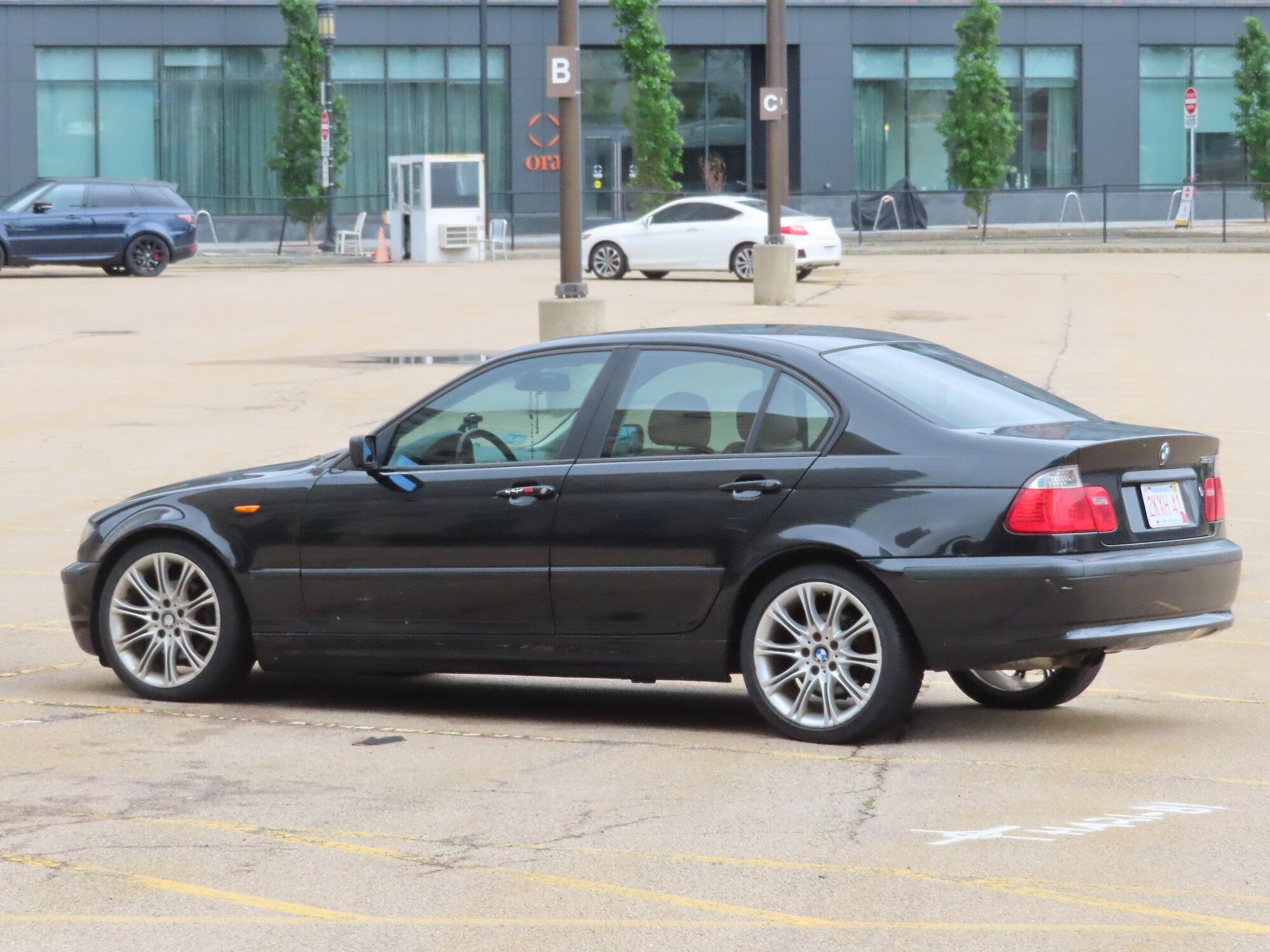 Black BMW 3 Series E46 sedan in a parking lot, side view
