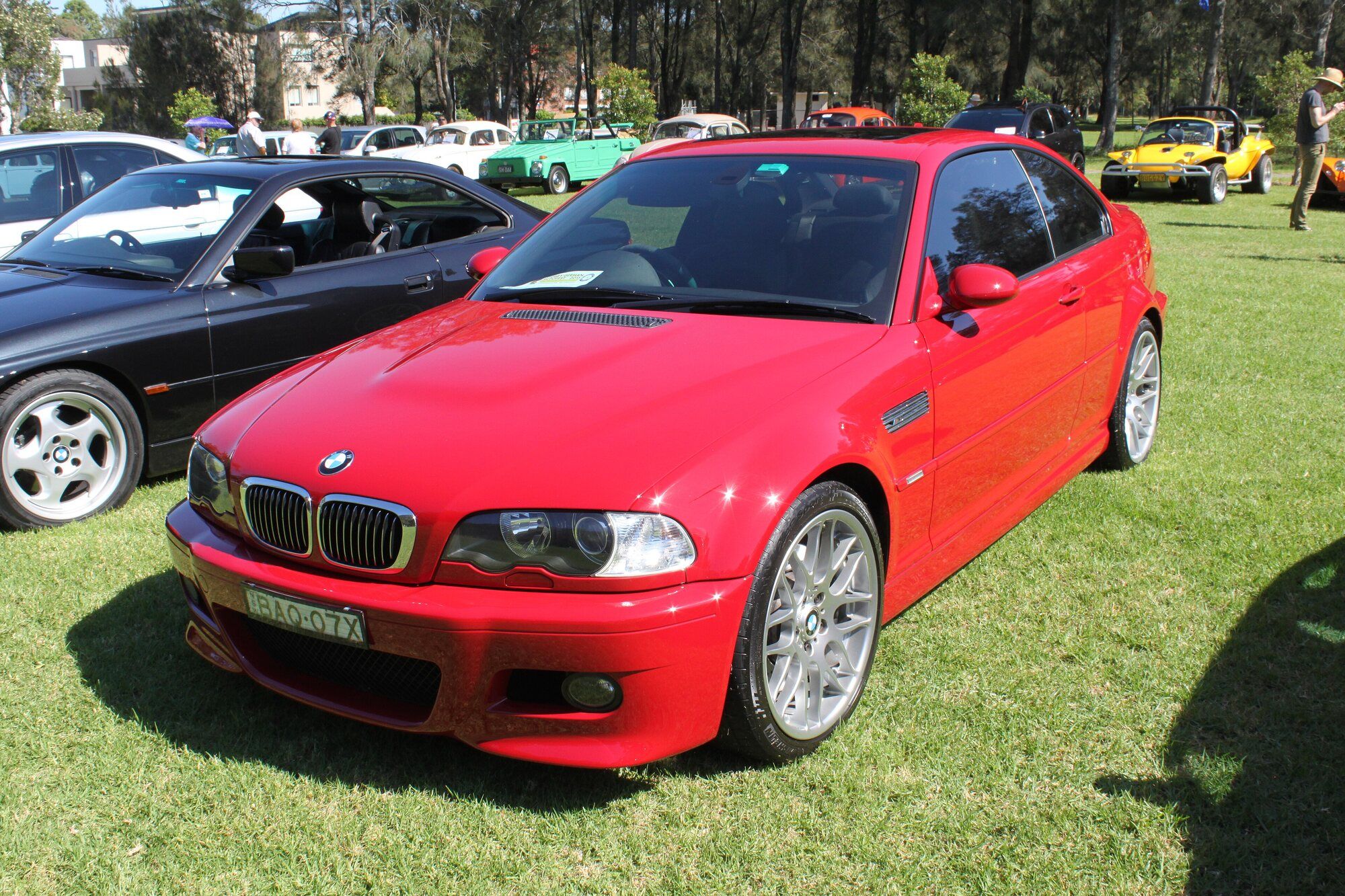 Red BMW M3 E46 coupe parked on grass, front three-quarter view