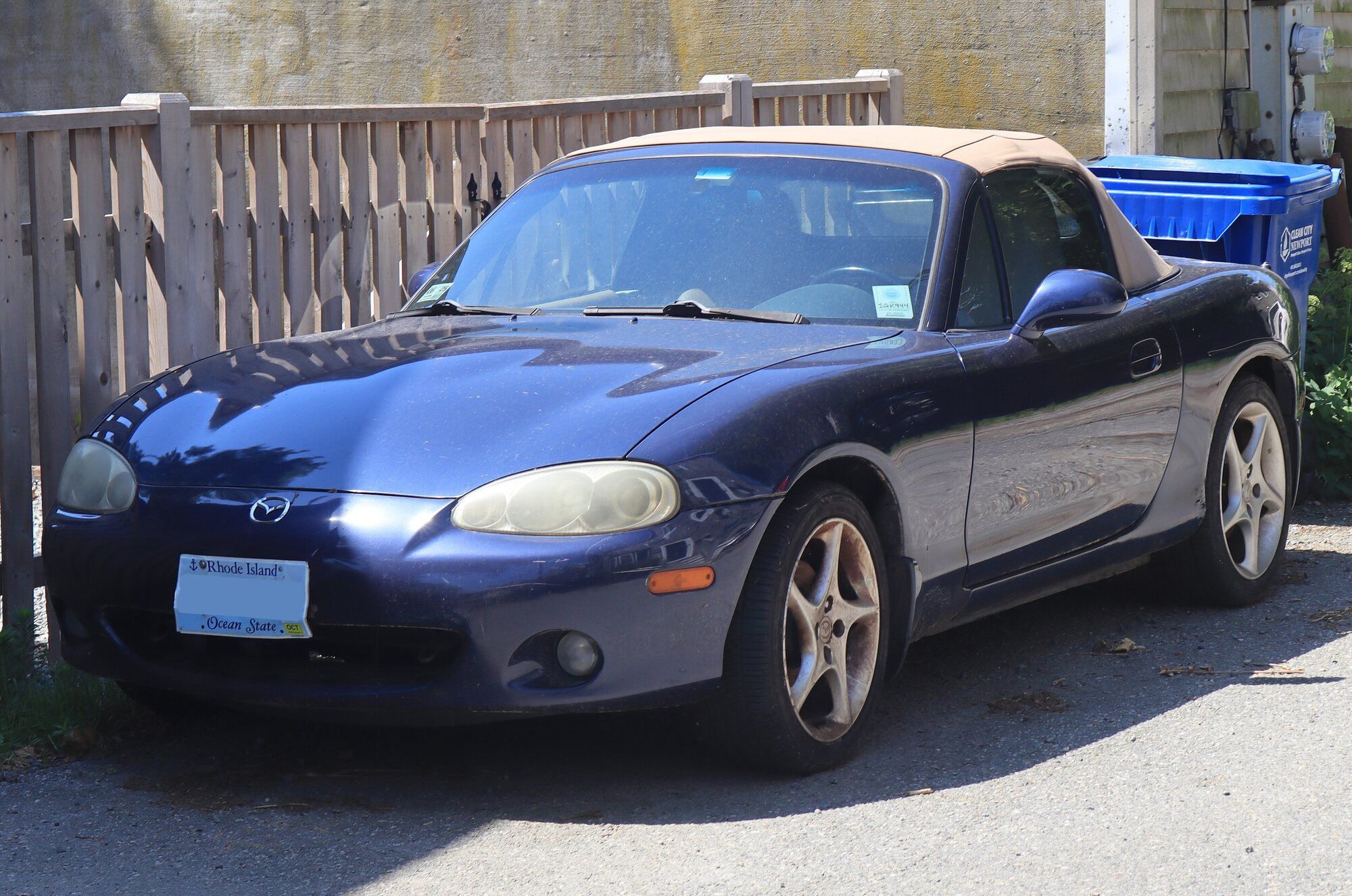 Dark blue 2001 Mazda Miata NB parked on a street, front three-quarter view, black soft top up