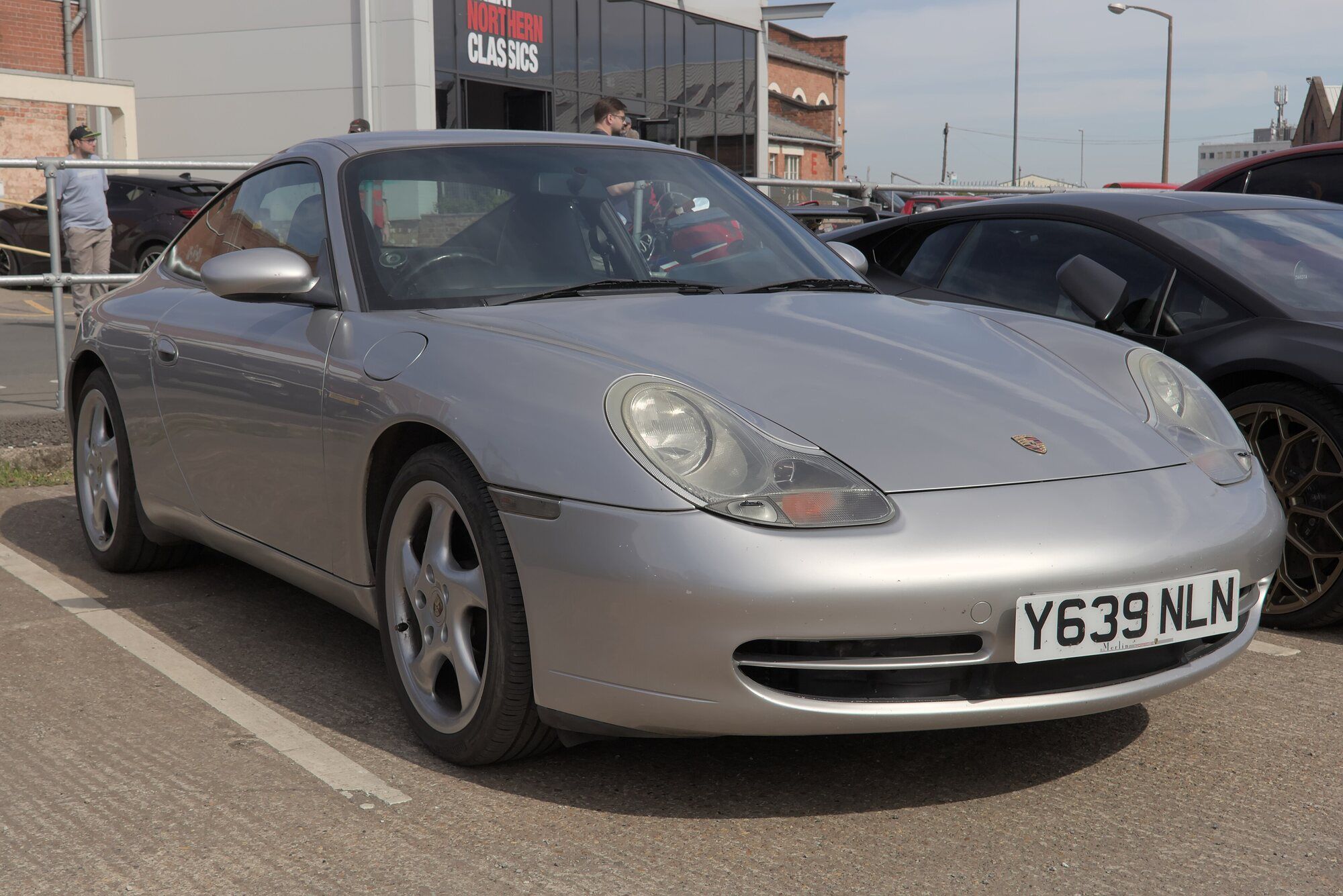 Silver Porsche 911 996 Carrera coupe parked, front three-quarter view with the early oval headlights