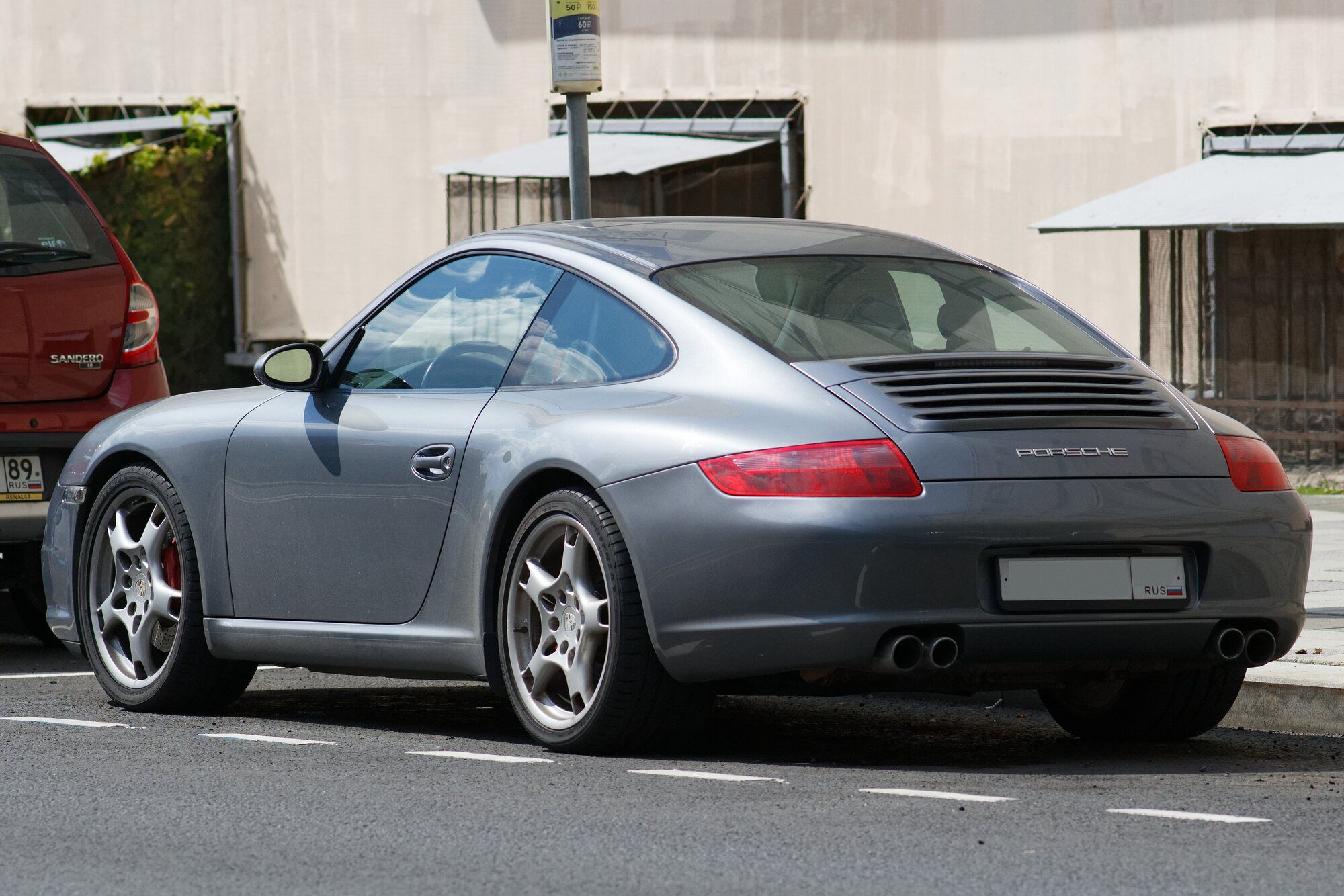 Grey Porsche 911 997 coupe parked on a street, rear three-quarter view